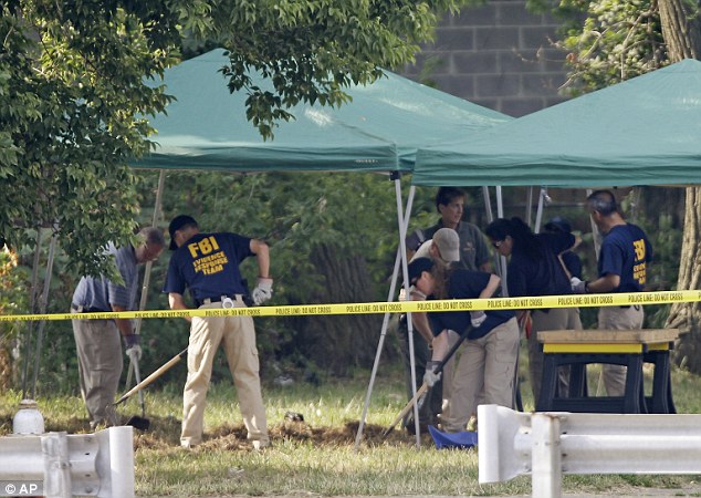 Combing: Cleveland police and FBI agents search a yard. There were apparently signs that dirt had recently been moved in the backyard of the house