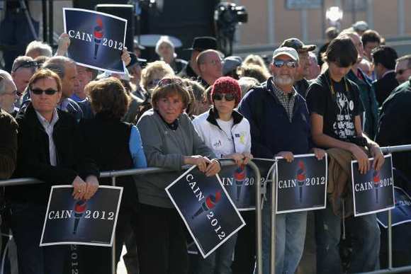 People wait outside holding signs before Republican presidential candidate Herman Cain speaks at the scheduled opening of a local campaign headquarters on Saturday in Atlanta.